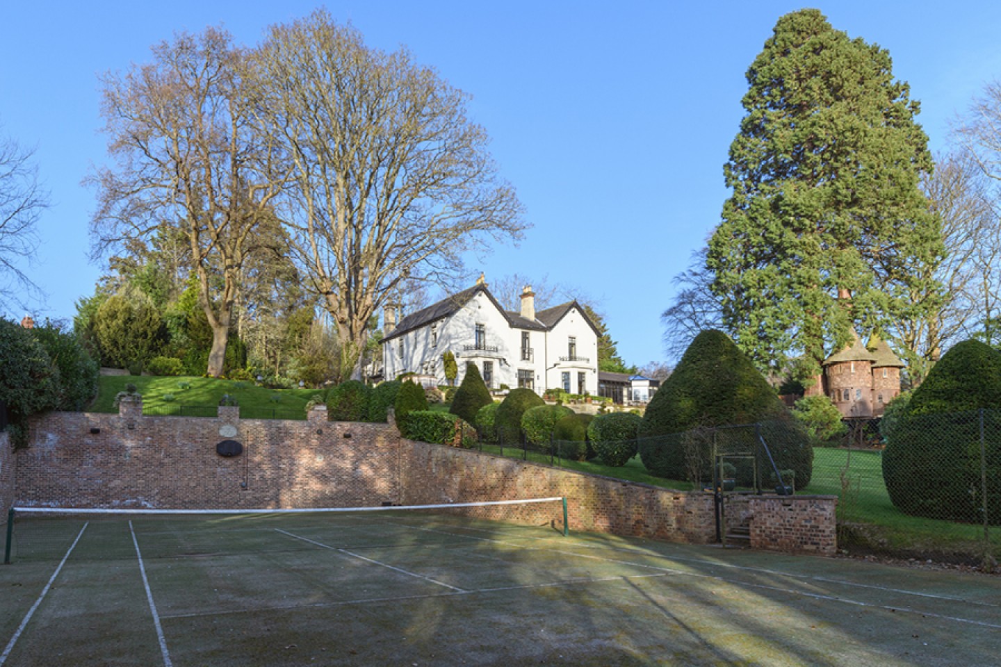All-weather tennis court with views up to the house